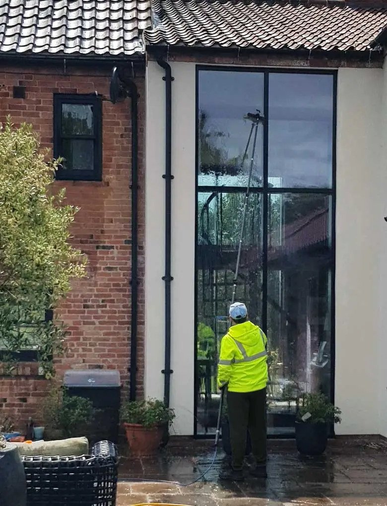A person cleaning an external window using a water-fed pole system