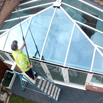 cleaner on ladder washes conservatory roof